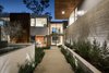 Modern home with Raised Planters, Flowers, Trees, Walkways, Front Yard, Outdoor, Gardens, and Stone Patio, Porch, Deck. The three-level, 13,777-square-foot compound on 1143 Ravoli Drive captivates with soaring walls of glass in nearly every room, framing panoramic canyon and mountain views. A 1,750-square-foot master suite offers maximum privacy and ocean views, in tandem with a jaw-dropping elevator in the walk-in closet that descends to a seasonal wardrobe closet. Photo of The Quintessence of Luxe California Living in Pacific Palisades