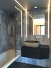 Modern home with Bath Room, Metal Counter, Laminate Counter, Tile Counter, Marble Counter, Stone Counter, Porcelain Tile Floor, Vessel Sink, Wall Mount Sink, Open Shower, Corner Shower, Ceiling Lighting, Drop In Tub, Wall Lighting, Accent Lighting, Marble Wall, Recessed Lighting, and Stone Tile Wall. Guest bathroom with marble walls, mirrored tub face, and natural stone lavatory Photo 7 of MB Residence (Nearing Completion)