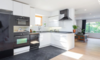 Modern home with Kitchen, White Cabinet, Ceiling Lighting, Light Hardwood Floor, Recessed Lighting, Refrigerator, Wall Oven, Dishwasher, Cooktops, Microwave, Range Hood, Ceramic Tile Backsplashe, Drop In Sink, and Undermount Sink. Kitchen Photo 4 of East Pender home