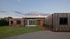 Modern home with Outdoor, Grass, Field, Shrubs, Front Yard, Hardscapes, Trees, Decking Patio, Porch, Deck, and Large Patio, Porch, Deck. Sunrise at Copperwood. The exterior is comprised of thermally treated Ash and white, cement panels. Photo 9 of Copperwood