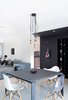 Modern home with Pendant Lighting, Table, Chair, Sectional, Wall Lighting, and Dining Room. The long hallway is an open plan with dining and living area combined, characterized by a large single piece sofa in grey velvet. The room is split by a square table in the middle with grey frosted glass and lean metal supports, adorned by four different chairs from Eames’ classics. The black La Stanza Dello Scirocco fruit bowl designed by Mario Trimarchi for Alessi is an art piece abstracted out of cards in an unstable balance, complimenting the table top. The London label Buster & Punch is admired for injecting a strong attitude towards craftsmanship in extra ordinary objects made for everyday use, complimenting the black and white decor with pendants and dimmers machined out of solid brass which gracefully ages with time. Photo of Living in Monochrome, far away from Nordic lands