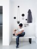 Modern home with Storage, Bench, Living Room, and Dining Room. There is a certain elegance in the randomness created by Muuto dots on one of the living room walls, the diversity in form and materials of the objects chosen, and the purpose behind. The Hanging Vessel fromMenu switches between a planter or a storage for stationery, with the carbon semi-circular vessel laying flat against the wall. Paired with a Bang & Olufsen speaker beautifully machined in Aluminium, a pair of sneakers and a jacket in grey mélange, with one dot left bare to celebrate its own design. Photo 5 of Living in Monochrome, far away from Nordic lands