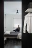 Modern home with Bedroom, Bed, Pendant Lighting, Dresser, and Painted Wood Floor. The master bedroom flooring is inspired by old church floors, with painted black floor boards and broken surfaces giving the room a rustic contrast to the satin white and black walls. The beds by Gruppo Euromobil in both the bedrooms feature a simple construction in a headless design with the plank directly resting on low sideboards, painted in neutral pastel tones and adorned by black linen. Light enters the room creating an interesting silhouette through the cellular window shades from Hunter Douglas. Photo 8 of Living in Monochrome, far away from Nordic lands