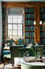 Modern home with Dining Room, Shelves, Rug Floor, Table, Chair, Wall Lighting, Bench, and Medium Hardwood Floor. In the Library, built-in bookcases and a long banquette (upholstered in Kravet’s Versailles Velvet fabric, color E25600) were installed on the far side of the room. Photo 8 of The Clifton