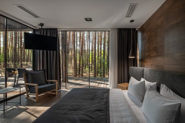 In the bedroom, a gray cotton upholstered headboard grounds the bed, and veneered oak plywood walls serve as a backdrop.