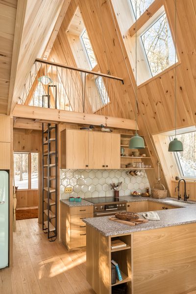 Oak cabinetry that was milled from the site is topped with Deer Isle granite. Locally manufactured tile from nearby Camden adds a textured sheen. And Muuto pendant lights hang over the bar.