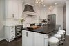 Modern home with Kitchen, Ice Maker, Pendant Lighting, Marble Counter, Range Hood, Range, Dark Hardwood Floor, Beverage Center, White Cabinet, Undermount Sink, Refrigerator, Microwave, Wine Cooler, and Ceramic Tile Backsplashe. Contrasting countertops and cabinetry bring a modern touch to an otherwise traditional kitchen in North Carolina. Photo of Chic Black and White Kitchen in Charlotte, NC