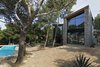 Modern home with Exterior, Stone Siding Material, Shingles Roof Material, House Building Type, and Wood Siding Material. Both facades completely open up through large glazing surfaces to the view of the pines trees and the hills beyond Photo 3 of The Wedge House