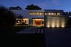 Modern home with Front Yard, Landscape Lighting, Trees, Exterior, House, and Concrete Siding Material. Night has fallen, front view of the House at Los Cisnes Photo 10 of House at Los Cisnes