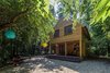 Modern home with House Building Type, Shingles Roof Material, Wood Siding Material, Outdoor, Side Yard, Trees, Front Yard, Wood Patio, Porch, Deck, Small Patio, Porch, Deck, Decking Patio, Porch, Deck, and Hanging Lighting. The House in the Woods is surrounded by a dense forest with winding paths leading up to it, so figure out how to transport the building materials to their final location proved to be an excellent challenge Photo of A Family Affair