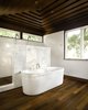 Modern home with Bath Room, Accent Lighting, Freestanding Tub, Wall Lighting, Open Shower, Stone Slab Wall, Pedestal Sink, One Piece Toilet, Ceiling Lighting, Recessed Lighting, and Medium Hardwood Floor. Master bath at Residence 1414 by Miró Rivera Architects Photo 11 of Residence 1414