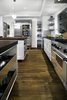 Modern home with Kitchen, Wine Cooler, Metal Cabinet, Refrigerator, Stone Counter, Ceiling Lighting, Accent Lighting, Microwave, Recessed Lighting, Wood Cabinet, Dishwasher, Subway Tile Backsplashe, Open Cabinet, Range Hood, Medium Hardwood Floor, Pendant Lighting, Undermount Sink, White Cabinet, and Range. Kitchen at Residence 1414 by Miró Rivera Architects Photo 6 of Residence 1414