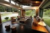 Modern home with Living Room, Bench, Sofa, Chair, Coffee Tables, Console Tables, Lamps, Pendant Lighting, Recessed Lighting, and Rug Floor. The most successful effort in sustainability is the use of natural light and air. In its opened up form, ie. with all its doors and windows opened up, it blends into a perfect continuum with the pristine surroundings. The interior spaces are well ventilated, shaded and protected from heat by the roof and double glazed openings, cutting down the energy use significantly. The totally glazed living room has completely openable/ foldable/ pivoted windows giving it an absolutely open to nature ventilation. Photo 2 of The Flying House