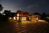Modern home with Outdoor, Front Yard, Garden, Trees, Shrubs, Grass, Gardens, Hardscapes, Walkways, Boulders, Flowers, Small Patio, Porch, Deck, Wood Patio, Porch, Deck, Metal Patio, Porch, Deck, Stone Patio, Porch, Deck, Pavers Patio, Porch, Deck, and Landscape Lighting. Most of the spaces in the residence have the luxury of viewing the sky above and ground beneath simultaneously. This visual connectivity, supplemented by the presence of lush greenery and water was a key component of the design conception and process. The glazed walls that rise from the lintel to the high roof facilitate an extended sky view from within giving the resemblance of wide opened eyes marveling at the sky expanse. Photo 3 of The Flying House