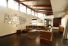 Modern home with Living Room, Bench, Coffee Tables, Console Tables, Sofa, Ceiling Lighting, Table Lighting, Pendant Lighting, and Rug Floor. The roofing system is a multi-layered composite one which has external aluminium and internal timber. Wooden planks and MS rafters enveloped by wood beneath the roof yields an inherent dynamism to the ceiling. The openings beneath the roof generate a play of light and shadow on the ceiling plane. Large overhangs that hang down from the roof cuts the direct light and helps reduce the solar gain through the clear. Photo 6 of The Flying House