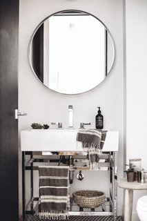 The stone-hued palette makes its way into the powder room where minimalist style is matched with luxurious textiles from Creative Women and silver finishings. A Pottery Barn vanity offers a foundation for a Dornbracht faucet and Grown Alchemist soap.