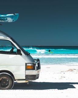 Out catching waves with home parked right on the shore. 