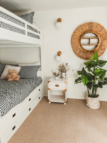 To maximize space in the kids' room, Thomas used a bunk and trundle full bed that fits adults as well as children. The beds are topped with organic checked sheets from Pottery Barn Kids and alpaca teddy bears from The Little Market. A Justina Blakeney wall hangings adds a pop of texture. “I wanted the room to be kid friendly but adult appropriate—so I kept the color palette neutral and chose pieces that would work for any guest, like this cute night stand, modern book shelf, and minimalistic reading lights (the Stella Sconce by Mitzi).”