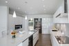 Modern home with Kitchen, Wall Oven, Range Hood, Wine Cooler, White Cabinet, Pendant Lighting, Recessed Lighting, Beverage Center, Undermount Sink, Range, Refrigerator, and Medium Hardwood Floor. Kitchen view Photo 9 of Khabensky Residence