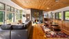 Modern home with Living Room, Medium Hardwood Floor, Wood Burning Fireplace, Shelves, Chair, Sectional, Bookcase, Table, Recessed Lighting, Lamps, Pendant Lighting, Floor Lighting, Rug Floor, and Standard Layout Fireplace. The energy-efficient Dickerman Residence by Richard Pedranti Architect boasts warm wood ceilings, midcentury-inspired furnishings, and a stately stone fireplace. Photo 7 of Dickerman Residence