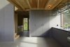 Modern home with Kitchen. Kitchen and furnishings are made of grey wood fiberboard. Over the entire kitchen counter there is an oblong window section that emits light through a roof-mounted kitchen shelf in steel and glass. In the background a glimpse of the cubbyhole/reading corner. Photo 9 of Späckhuggaren