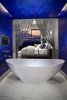 Modern home with Bath Room, Porcelain Tile Floor, Soaking Tub, and Recessed Lighting. Orienting the master suite along the rear of the home and providing floor-to-ceiling glazing allows homeowners to fall asleep looking at the twinkling lights. Rather than closing the master bath off from the views, designers opted to create an enclave, connecting the bedroom and bathroom, in which to place the deep soaking tub. A pop of color delineates the space uniquely from both the bedroom and the rest of the bathroom area. Photo 10 of Vu at MacDonald Highlands