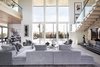 Modern home with Living Room, Chair, Sofa, Sectional, Gas Burning Fireplace, Ceiling Lighting, Accent Lighting, Porcelain Tile Floor, and Standard Layout Fireplace. A floor-to-ceiling and wall-to-wall window looks directly out to a covered loggia in the backyard and brightens the space with sunlight. Photo 6 of BUILDER Chōwa Concept Home