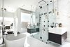 Modern home with Bath Room, Porcelain Tile Wall, Freestanding Tub, Wall Mount Sink, Ceiling Lighting, Pendant Lighting, Accent Lighting, Enclosed Shower, Marble Counter, and Porcelain Tile Floor. Ryan Young Interiors created a luxurious primary bath where a book-matched porcelain slab is the backsplash for the glass-enclosed shower. Dual vanities float on either side of the shower, while the freestanding tub sits adjacent to the sinks and shower. Photo 8 of BUILDER Chōwa Concept Home