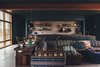 Modern home with Living Room, Sectional, Ceiling Lighting, Pendant Lighting, Table Lighting, Concrete Floor, and Wood Burning Fireplace. Kitchen, dining, and living area with exposed corten steel main beam. Photo 4 of The Caudill House