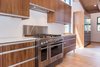 Modern home with Kitchen, Engineered Quartz Counter, Quartzite Counter, Wood Cabinet, Medium Hardwood Floor, Ceiling Lighting, Pendant Lighting, Recessed Lighting, Refrigerator, Range, Range Hood, Microwave, Dishwasher, and Undermount Sink. Stainless DCS and Fisher Paykel appliances in kitchen with walnut cabinets Photo 6 of Mammoth Modern House 1