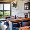 Modern home with Kitchen, Microwave, Pendant Lighting, Dark Hardwood Floor, Beverage Center, Refrigerator, Wood Counter, and Drop In Sink. The hardwood floors are original to the container and have traveled the world over Photo 9 of Flophouze Hotel