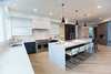 Modern home with Kitchen, Engineered Quartz Counter, Quartzite Counter, White Cabinet, Wood Cabinet, Light Hardwood Floor, Ceiling Lighting, Pendant Lighting, Accent Lighting, Refrigerator, Microwave, Dishwasher, Cooktops, Range, Drop In Sink, and Range Hood. Sea Star Kitchen - After Photo 3 of Sea Star - Modernization Transformation
