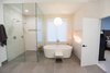 Modern home with Bath Room, Engineered Quartz Counter, Quartzite Counter, Porcelain Tile Floor, Wall Mount Sink, Freestanding Tub, Open Shower, Ceiling Lighting, Accent Lighting, Pendant Lighting, One Piece Toilet, and Porcelain Tile Wall. Sea Star Master Bathroom - After Photo of Sea Star Master Bathroom - Hidden Potential