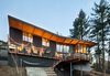 Modern home with Exterior, Wood Siding Material, House Building Type, Butterfly RoofLine, and Brick Siding Material. Built with a 15-degree bend in the center, the design helps the home conform to the lot while also enveloping outdoor decks. The south and east rooflines cantilever dramatically, offering shade over the 21-foot-high windows in the summer. Photo 4 of The Greenhills House