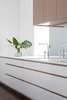 Modern home with Kitchen, Quartzite Counter, White Cabinet, Wood Cabinet, Light Hardwood Floor, Mirror Backsplashe, Recessed Lighting, Undermount Sink, and Medium Hardwood Floor. Mirrored backsplash deflects light from the opposite window and softens a typically, hard, utilitarian surface. Photo 4 of Coach House