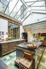 Modern home with Kitchen, Wall Lighting, and Ceramic Tile Floor. On a sought after an idyllic island in the center of Amsterdam an old warehouse, formerly in use as a pillow factory and a garage has been converted to a warm and eclectic family home. The kitchen features a mixture of green tiles, green painted mullions, and exposed wood beams for a warm, soft feeling that contrast sharply with the more industrial stainless steel island. The kitchen island incorporates a stove top and storage, and benefits from natural light from the skylight overhead. Photo 14 of The Prinseneiland House