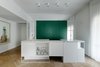 Modern home with Kitchen, Granite Counter, Colorful Cabinet, Medium Hardwood Floor, Ceiling Lighting, Refrigerator, Wall Oven, Microwave, Dishwasher, Beverage Center, and White Cabinet. kitchen- green cube storage containing two refrigerators inside, a water bar, a coffee machine as well as dishes and food supply.
The cube was then "wrapped around" by a glass vitrine divided by stone-white colored Belgium profiles with two entries one on each side of the cube leading to a family-room.
Photo 2 of Colorfull in the white city