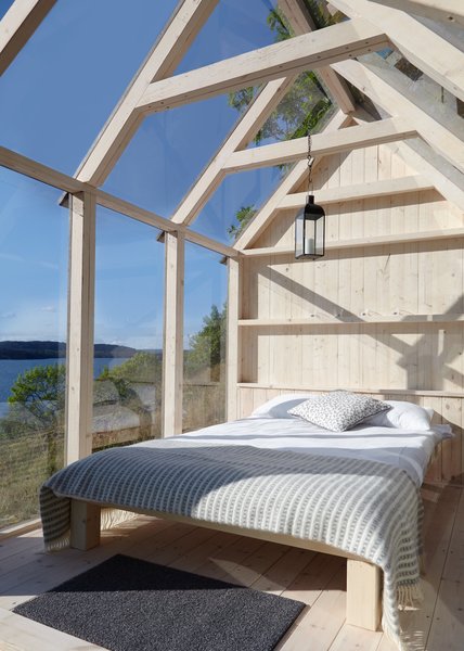 A lantern-style pendant outlined in black rests in stark contrast with its surroundings in this serene, minimalist cabin. The contrast seen here is one of our favorite bedroom lighting ideas.