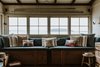 Modern home with Living Room, Stools, Storage, Bench, Medium Hardwood Floor, and Wall Lighting. A full-length window seat overlooks views of the beach and the bay. Photo 8 of The Little Black Shack