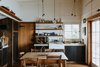 Modern home with Kitchen, Medium Hardwood Floor, Microwave, Drop In Sink, Open Cabinet, Pendant Lighting, and Concrete Counter. Two French doors open up the open-plan kitchen and dining area to a covered outdoor terrace overlooking the water. Photo 9 of The Little Black Shack