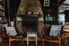 Modern home with Living Room, Medium Hardwood Floor, Chair, Coffee Tables, Wood Burning Fireplace, and Shelves. Sea breezes keep The Little Black Shack cool in summer, while a hand-built sandstone fireplace warms the property in winter. Photo 7 of The Little Black Shack