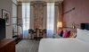 Modern home with Bedroom, Carpet Floor, Night Stands, Bed, Lamps, Chair, Floor Lighting, and Wall Lighting. Exposed brick walls can be seen in the Premium King Suite, which overlooks views of Magazine Street. Photo 5 of The Eliza Jane