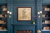 Modern home with Office and Shelves. A closer look at the front desk with painted paneled walls, built-in bookshelves. a decorative fireplace, and a framed sketch of a figure evocative of Eliza Jane. Photo 2 of The Eliza Jane