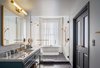 Modern home with Bath Room, Freestanding Tub, Porcelain Tile Floor, Enclosed Shower, Subway Tile Wall, Wall Lighting, Marble Counter, and Undermount Sink. The luxurious Publisher Suite bath features a free-standing bathtub next to a large window with a privacy curtain. Photo 8 of The Eliza Jane