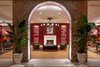 Modern home with Living Room, Medium Hardwood Floor, Sofa, Recessed Lighting, Coffee Tables, Chair, Wall Lighting, End Tables, and Rug Floor. An original brick wall with an arch opening frames views of The Press Room, a cozy lounge lined with paneled walls painted a deep cranberry hue to match the Press Room bar front. Photo 11 of The Eliza Jane
