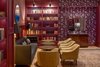 Modern home with Living Room, Sofa, Lamps, Chair, Wall Lighting, Medium Hardwood Floor, Table Lighting, Rug Floor, and Floor Lighting. The Press Room is dressed with leather and velvet furnishings, antiques, books and typewriters. Photo 13 of The Eliza Jane