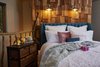 Modern home with Bedroom, Medium Hardwood Floor, Wall Lighting, Dresser, and Bed. A Bolsover upholstered bed frame is set against a shingle accent wall fitted with Industrial 1 Light Armed sconces. Photo 5 of Ravendere Retreats
