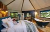 Modern home with Bedroom, Wall Lighting, Dresser, Medium Hardwood Floor, and Bed. The domed master bedroom—which has a king-size bed—on the second floor provides an immersive experience in the treetop canopy thanks to the five large windows that punctuate the hexagonal space. Photo 4 of Ravendere Retreats