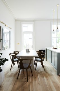 The kitchen and dining area are made to feel bright and airy with minimalist decor and walls painted Sherwin Williams Origami White. The lights hanging over the island are Allied Maker's Blobe pendants. 