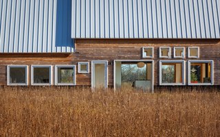 Galvalume standing metal seam roofs reflect the sunlight, while horizontal planks of natural cedar siding are left untreated to weather.